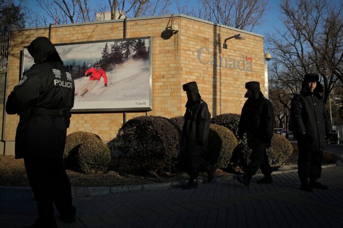 Police officers outside the Canadian Embassy in Beijing. Image: Andy Wong/Associated Press