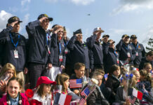 Chasing Demons: 75 Years On, D-Day Haunts, Drives Its Vets World War II veterans from the United States salute as they pose with local school children at the Normandy American Cemetery in Colleville-sur-Mer, Normandy, France, Monday, June 3, 2019. France is preparing to mark the 75th anniversary of the D-Day invasion which took place on June 6, 1944. Photo: Rafael Yaghobzadeh / AP