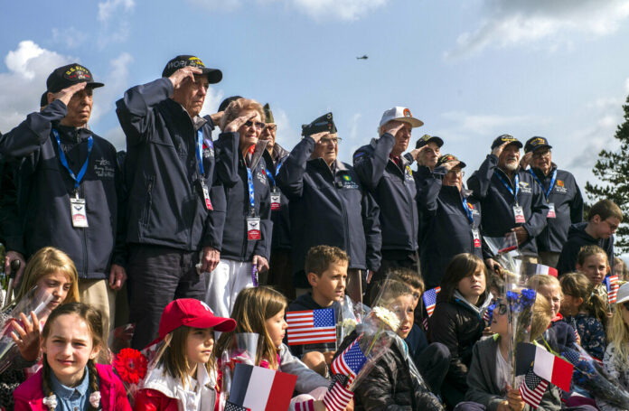 World War II veterans from the United States salute as they pose with local school children at the Normandy American Cemetery in Colleville-sur-Mer, Normandy, France, Monday, June 3, 2019. France is preparing to mark the 75th anniversary of the D-Day invasion which took place on June 6, 1944. Photo: Rafael Yaghobzadeh / AP