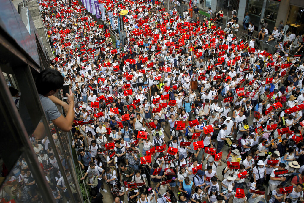 A man uses a smartphone to take photo of protesters take part in a rally against the proposed amendments to extradition law on a street in Hong Kong, Sunday, June 9, 2019. The amendments have been widely criticized as eroding the semi-autonomous Chinese territory's judicial independence by making it easier to send criminal suspects to mainland China, where they could face vague national security charges and unfair trials. Photo: Kin Cheung / AP