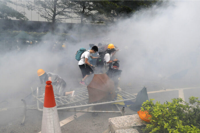 Protesters react to a cloud of tear gas near the Legislative Council in Hong Kong, Wednesday, June 12, 2019. Photo: Kin Cheung / AP