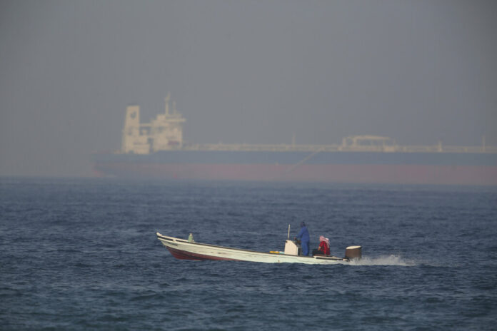 A fishing boat speeds past an oil tanker in the distance in Fujairah, United Arab Emirates, Saturday, June 15, 2019. The Kokuka Courageous, one of two oil tankers targeted in an apparent attack in the Gulf of Oman, was brought to the United Arab Emirates' eastern coast Saturday. Photo: Jon Gambrell / AP