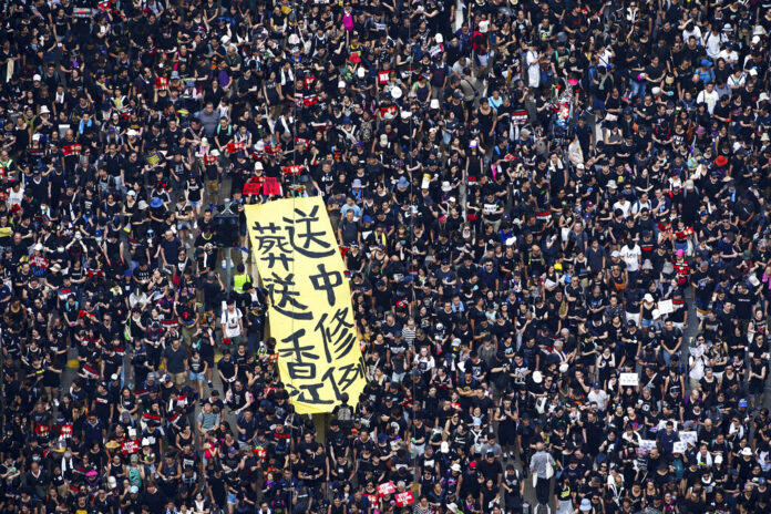 Tens of thousands of protesters carry posters and banners march through the streets as they continue to protest an extradition bill, Sunday, June 16, 2019, in Hong Kong. Image: Associated Press