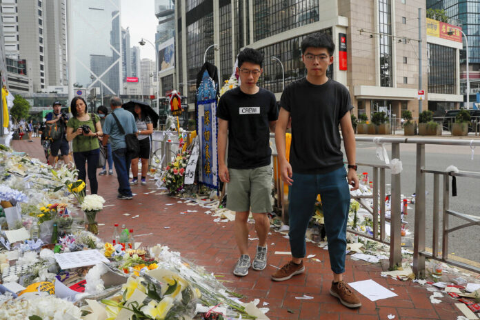 Pro-democracy activist Joshua Wong, right, is accompanied by Nathan Law as they pay respect to a protester who fell to his death after hanging a protest banner against an extradition bill in Hong Kong, Monday, June 17, 2019. Photo: Kin Cheung / AP