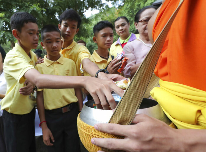 Members of the Wild Boars soccer team who were rescued from a flooded cave, offer foods to a Buddhist monk near the Tham Luang cave in Mae Sai, Chiang Rai province, Thailand Monday, June 24, 2019. Photo: Sakchai Lalit / AP