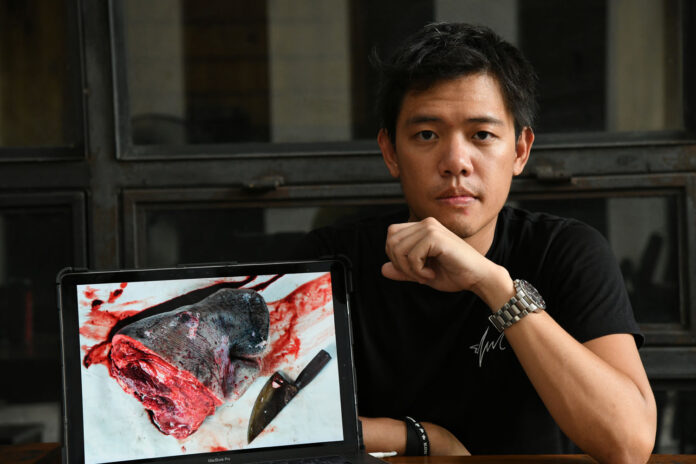 Sirachai Arunrugstichai with a photo of a dugong decapitated for an autopsy.