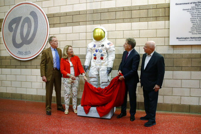 In this June 4, 2019 file photo, Washington Nationals senior vice president Gregory McCarthy, from left, Ellen Stofan of the National Air and Space Museum, statue donor Allan Holt and Nationals owner Mark Lerner unveil a statue of Neil Armstrong's Apollo 11 spacesuit before an interleague baseball game between the Chicago White Sox and the Nationals in Washington. It was unveiled as part of the 