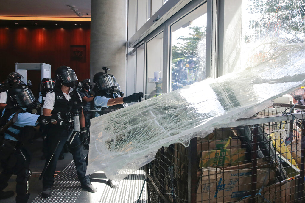 Police officers spray pepper spray as protesters use a cart to ram into the glass wall of the Legislative Council in Hong Kong on Monday, July 1, 2019. The embattled leader of Hong Kong pledged Monday to be more responsive to public sentiment, as police faced off with protesters on the 22nd anniversary of the former British colony's return to China. Photo: Steve Leung/HK01 via AP