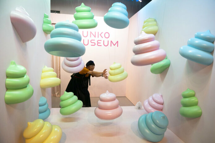 In this Tuesday, June 18, 2019, photo, a woman jokingly poses with large poop-shaped figurines at the Unko Museum in Yokohama, south of Tokyo. In a country known for its cult of cute, even poop is not an exception. A pop-up exhibition at the Unko Museum in the port city of Yokohama is all about unko, a Japanese word for poop. The poop installations there get their cutest makeovers. They come in the shape of soft cream, or cupcake toppings. Photo: Jae C. Hong / AP