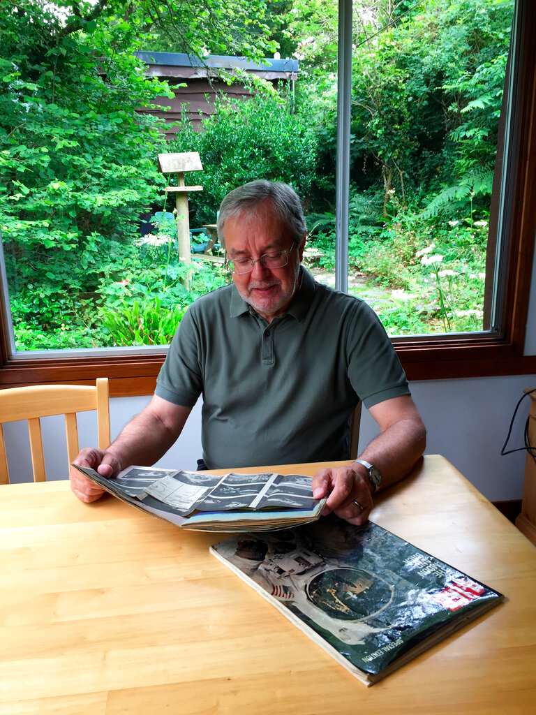 This June 25, 2019 photo provided by Peter Cowin shows him looking over Apollo 11 memorabilia at his home in Cheltenham, England. Photo: Courtesy Peter Cowin via AP