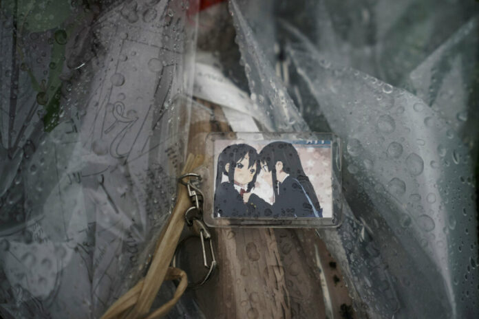 A keychain with a cartoon image is placed on top of flowers placed near the Kyoto Animation Studio building destroyed in an attack Friday, July 19, 2019, in Kyoto, Japan. Photo: Jae C. Hong / AP