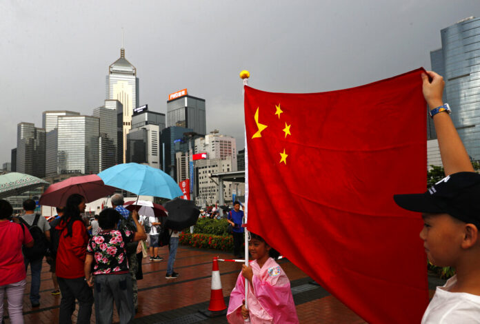 Pro-China supporters raise a China national flag during a counter-rally in support of the police in Hong Kong Saturday, July 20, 2019. Police in Hong Kong have raided a homemade-explosives manufacturing lab ahead of another weekend of protests in the semi-autonomous Chinese territory. Photo: Vincent Yu / AP
