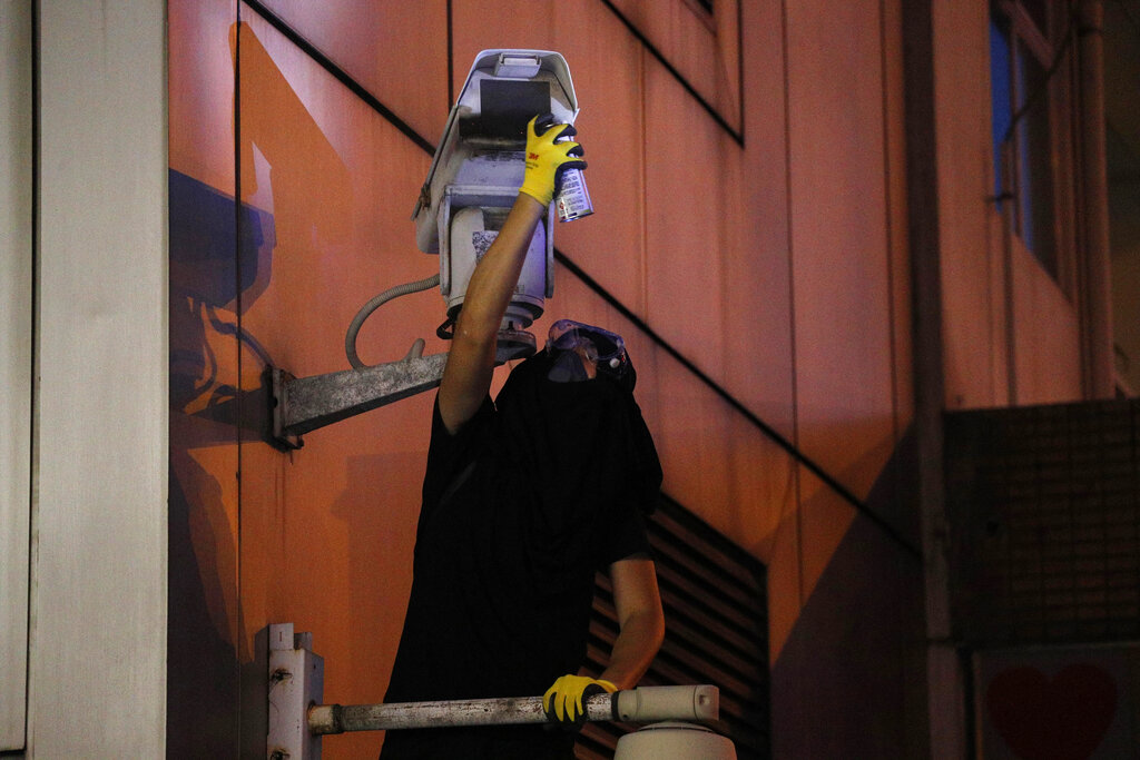 A protester spray paints the view of the surveillance camera outside the Chinese Liaison Office in Hong Kong, Sunday, July 21, 2019. Protesters in Hong Kong pressed on Sunday past the designated end point for a march in which tens of thousands repeated demands for direct elections in the Chinese territory and an independent investigation into police tactics used in previous demonstrations. Photo: Bobby Yip / AP