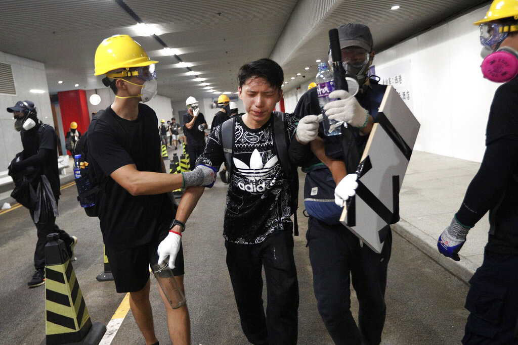 A protester reacts in pain from tear gas fired by policemen on a street in Hong Kong, Sunday, July 21, 2019. Hong Kong police have thrown tear gas canisters at protesters after they refused to disperse. Hundreds of thousands of people took part in a march Sunday to call for direct elections and an independent investigation into police tactics used during earlier pro-democracy demonstrations. Police waved a black warning flag Sunday night before lobbing the canisters into a crowd of protesters. Photo: Bobby Yip / AP