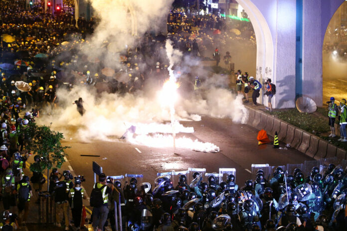 Protesters are engulfed by teargas during a confrontation with riot police in Hong Kong Sunday, July 21, 2019. Hong Kong police launched tear gas at protesters Sunday after a massive pro-democracy march continued late into the evening. The action was the latest confrontation between police and demonstrators who have taken to the streets to protest an extradition bill and call for electoral reforms in the Chinese territory. Photo: Lo Kwanho / HK01 via AP