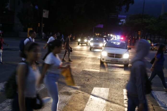 People cross a street during a blackout in Caracas, Venezuela, Monday, July 22, 2019. The lights went out across much of Venezuela Monday, reviving fears of the blackouts that plunged the country into chaos a few months ago as the government once again accused opponents of sabotaging the nation's hydroelectric power system. Photo: Ariana Cubillos / AP