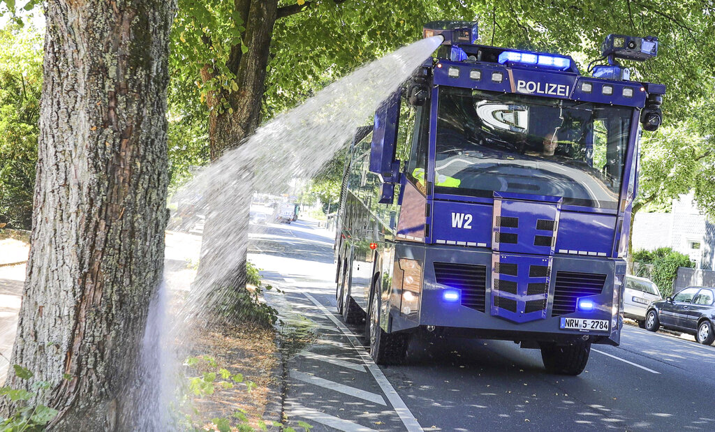 A water canon of the German police waters trees in Wuppertal, western Germany, Wednesday, July 24, 2019. Hot temperatures are expected all over Europe during the next days. Photo: Claudia Otte / dpa via AP