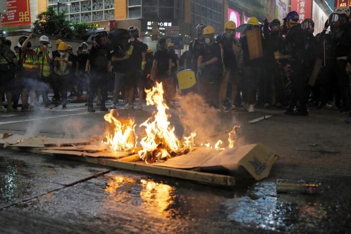 Protesters burn cardboard to form a barrier as they confront with police in Hong Kong on Saturday, Aug. 3, 2019. (AP Photo/Kin Cheung)