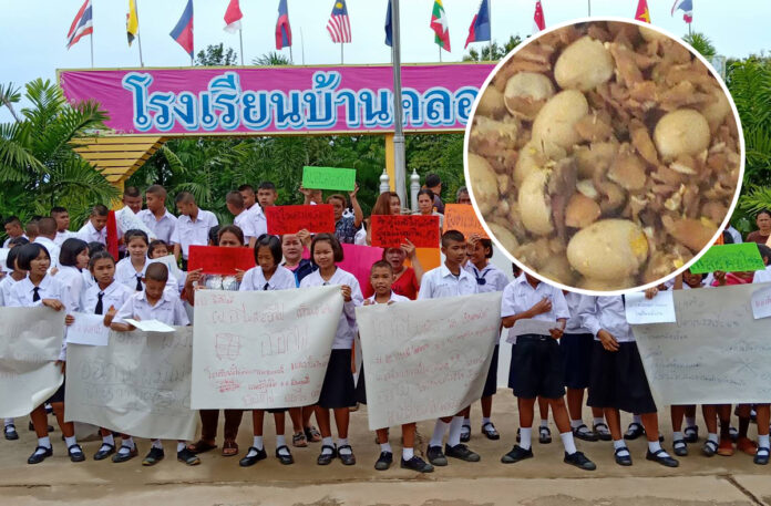 Students at Baan Khlong 12 School on August 5, 2019 hold signs asking their school director to resign for his suspected involvement in a school lunch that served rotten eggs.