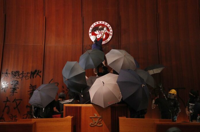 In this July 1, 2019, file photo, protesters deface the Hong Kong logo at the Legislative Council to protest against the extradition bill in Hong Kong. Photo: Vincent Thian Yu, File / AP