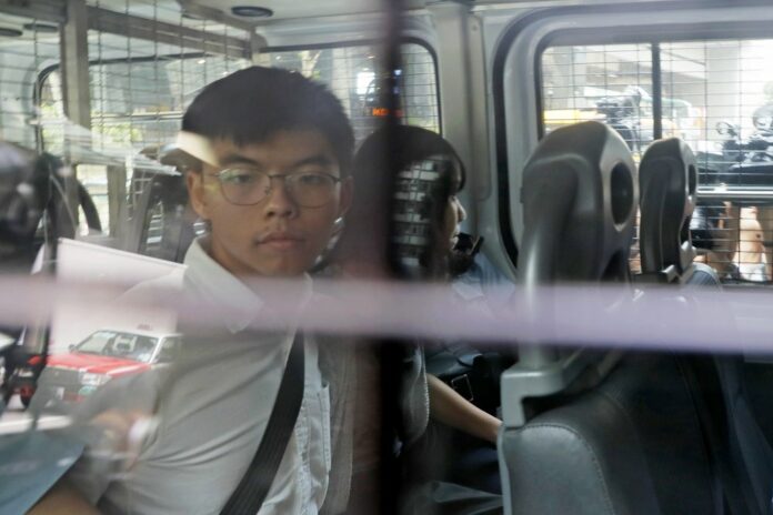 Pro-democracy activists Joshua Wong, left, and Agnes Chow, are escorted in a police van at a district court in Hong Kong, Friday, Aug. 30, 2019. (AP Photo/Kin Cheung)