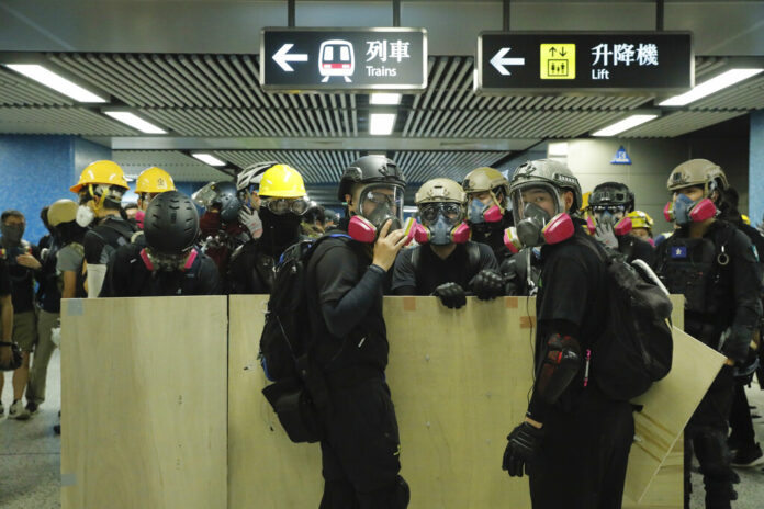 Protesters with makeshift shields pass through a subway station on their way to a police station in Hong Kong on Sunday, Aug. 4, 2019. Photo: Kin Cheung / AP