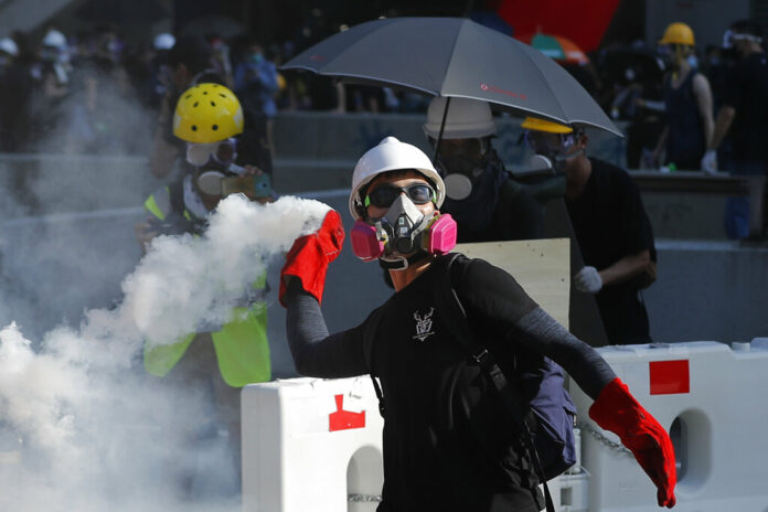 A protester throws back a tear gas canister in Hong Kong on Monday, Aug. 5, 2019. Droves of protesters filled public parks and squares in several Hong Kong districts on Monday in a general strike staged on a weekday to draw more attention to their demands that the semi-autonomous Chinese city's leader resign. Photo: Vincent Thian / AP