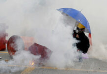 China Warns Hong Kong Protesters That Punishment Is Coming A protester is shrouded by tear gas in Hong Kong, Monday, Aug. 5, 2019. Droves of protesters filled public parks and squares in several Hong Kong districts on Monday in a general strike staged on a weekday to draw more attention to their demands that the semi-autonomous Chinese city's leader resign. Photo: Kin Cheung / AP