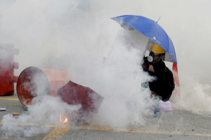 A protester is shrouded by tear gas in Hong Kong, Monday, Aug. 5, 2019. Droves of protesters filled public parks and squares in several Hong Kong districts on Monday in a general strike staged on a weekday to draw more attention to their demands that the semi-autonomous Chinese city's leader resign. Photo: Kin Cheung / AP