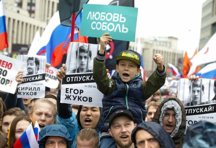 People with posters show portraits of detained protesters and a boy with a poster reads Lyubov Sobol react during a protest in Moscow, Russia, Saturday, Aug. 10, 2019. Tens of thousands of people rallied in central Moscow for the third consecutive weekend to protest the exclusion of opposition and independent candidates from the Russian capital's city council ballot. Photo: Alexander Zemlianichenko / AP