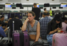 Hong Kong Airport Protest Shutdown Tarnishes Business Image Australian Penny Tilley, center, reacts next to stranded travelers at the closed check-in counters at the Hong Kong International Airport, Monday, Aug. 12, 2019. One of the world's busiest airports canceled all flights after thousands of Hong Kong pro-democracy protesters crowded into the main terminal Monday afternoon. Photo: Kin Cheung / AP