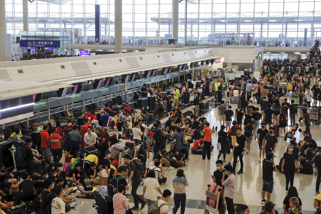 Protesters gather near the stranded travelers at the closed check-in counters during a protest at the Hong Kong International Airport, Monday, Aug. 12, 2019. Photo: Kin Cheung / AP