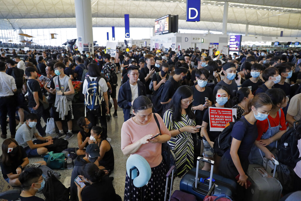 Stranded travelers using smartphones are surrounded by protesters during a protest at the Hong Kong International Airport, Monday, Aug. 12, 2019. Photo: Kin Cheung / AP
