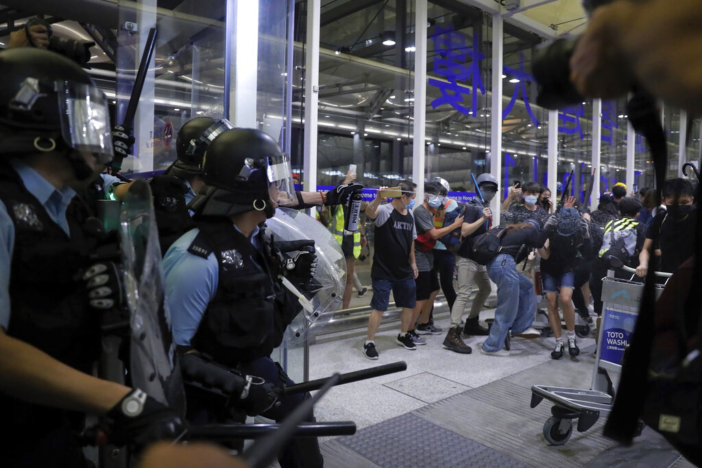 Policemen in riot gears use pepper spray on the protesters during a demonstration at the Airport in Hong Kong, Tuesday, Aug. 13, 2019. Chaos has broken out at Hong Kong's airport as riot police moved into the terminal to confront protesters who shut down operations at the busy transport hub for two straight days. Photo: Kin Cheung / AP