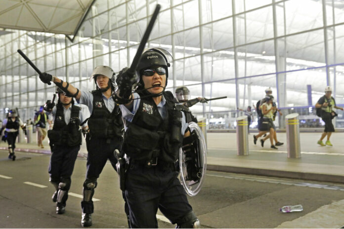 Policemen with batons and shields shout at protesters during a demonstration at the Airport in Hong Kong, Tuesday, Aug. 13, 2019. Riot police clashed with pro-democracy protesters at Hong Kong's airport late Tuesday night, a chaotic end to a second day of demonstrations that caused mass flight cancellations at the Chinese city's busy transport hub. Photo: Vincent Yu / AP