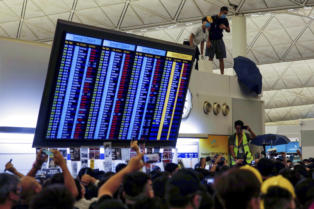 Protester use an umbrellas to block surveillance cameras during a demonstration at the Airport in Hong Kong, Tuesday, Aug. 13, 2019. Riot police clashed with pro-democracy protesters at Hong Kong's airport late Tuesday night, a chaotic end to a second day of demonstrations that caused mass flight cancellations at the Chinese city's busy transport hub. Photo: Vincent Yu / AP