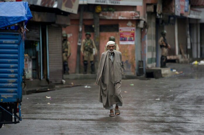 A Kashmiri man walks as Indian paramilitary soldiers stand guard during security lockdown in Srinagar, Indian controlled Kashmir, Wednesday, Aug. 14, 2019. Photo: Dar Yasin / AP