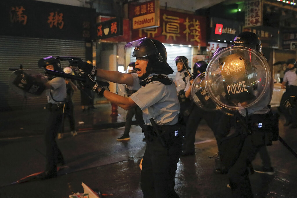 Policemen pull out their guns after a confrontation with demonstrators during a protest in Hong Kong, Sunday, Aug. 25, 2019. Hong Kong police have rolled out water cannon trucks for the first time in this summer's pro-democracy protests. The two trucks moved forward with riot officers Sunday evening as they pushed protesters back along a street in the outlying Tsuen Wan district. Photo: Vincent Yu / AP