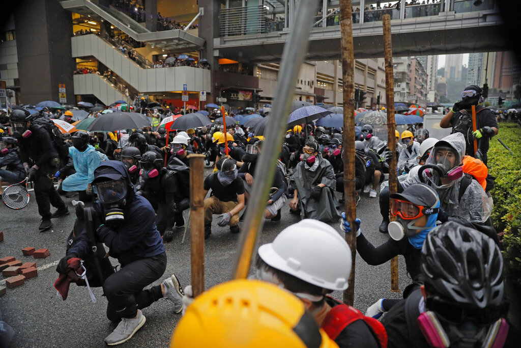 Protesters crouch behind a barricade during a protest in Hong Kong, Sunday, Aug. 25, 2019. Police in Hong Kong used tear gas Sunday to clear pro-democracy demonstrators who had taken over a street and brought out water cannon trucks for the first time in the summer long protests. Photo: Kin Cheung / AP