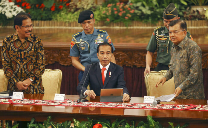 Indonesia President Joko Widodo, center, takes his seat as his deputy Jusuf Kalla, right, and Agrarian and Spatial Planning Minister Sofyan Djalil, left, looks on before a press conference, at the palace in Jakarta, Indonesia, Monday, Aug. 26, 2019. Photo: Achmad Ibrahim / AP