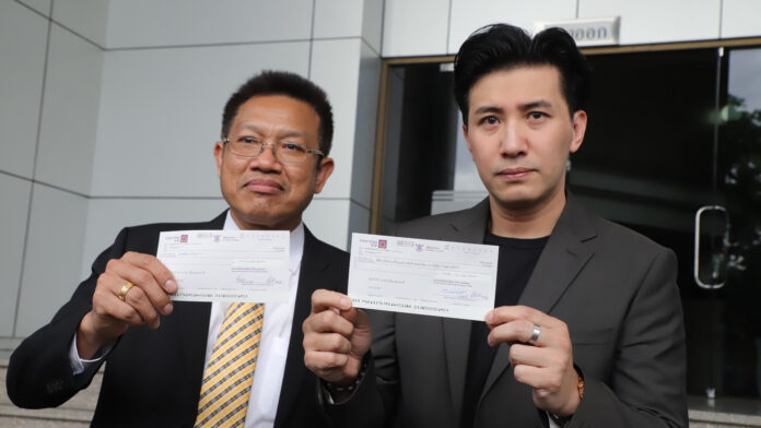 Decha Kittivittayanan, left, and Kanchai “Noom” Kamnerdploy, right, holding the cheques for compensation in front of the Civil Court on August 6.