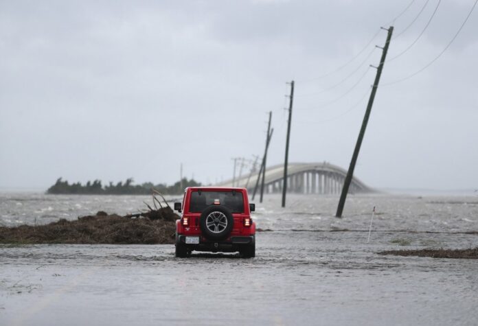 In this Friday, Sept. 6, 2019 file photo, storm surge from Hurricane Dorian blocks Cedar Island off from the mainland on NC 12 in Atlantic Beach, N.C., after Hurricane Dorian passed the coast. (AP Photo/Tom Copeland)