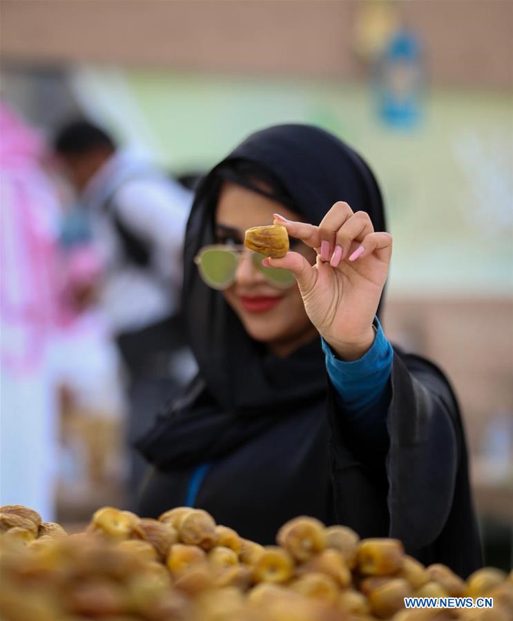 A woman shows a date at a seasonal date market in the city of Buraydah, north of Riyadh, Saudi Arabia, on Aug. 29, 2019. Photo: CIC/Handout via Xinhua