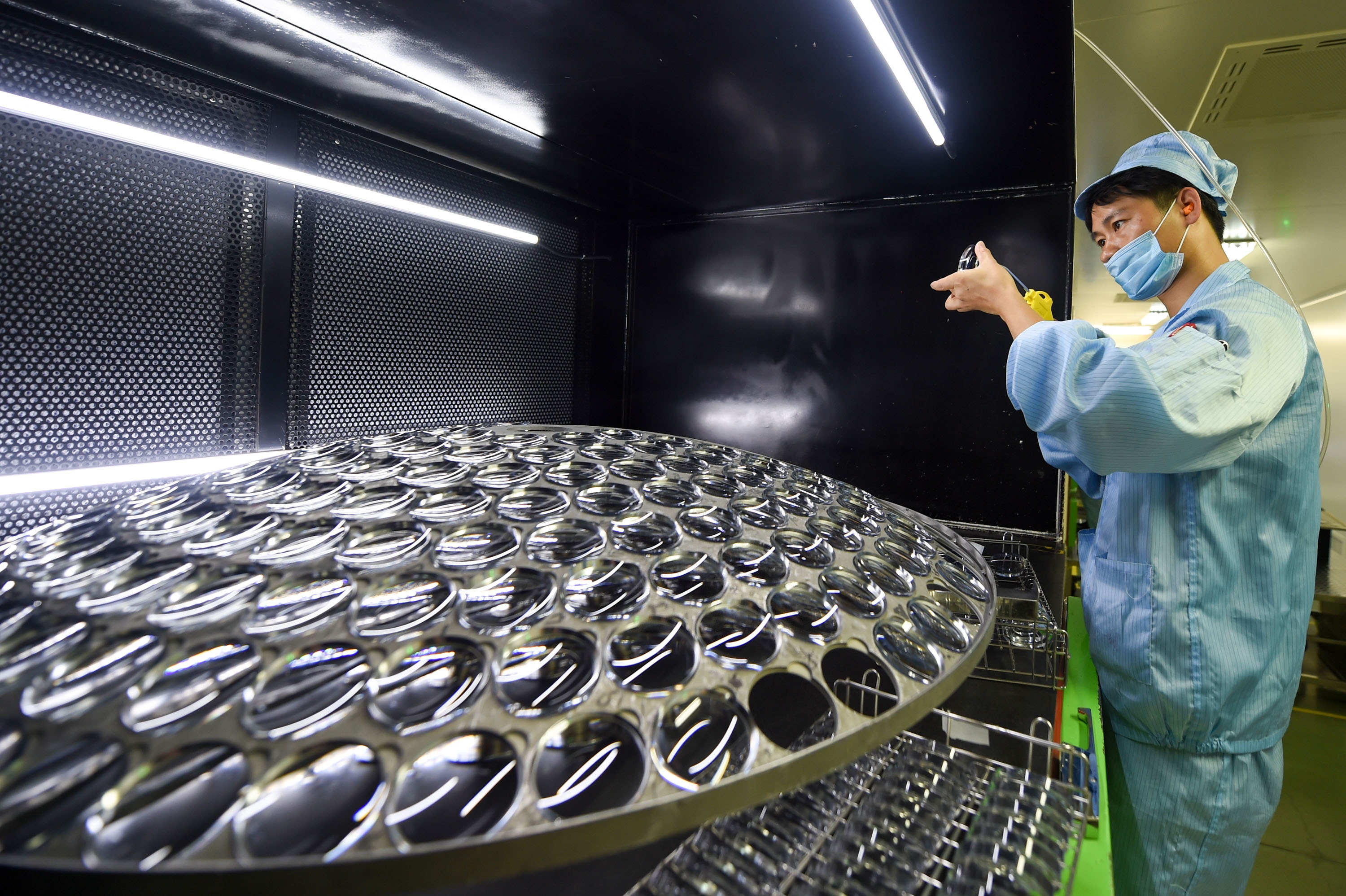 A worker adds film onto glasses at a glasses company in Danyang City, east China's Jiangsu Province, July 12, 2018. Photo: Li Bo / Xinhua