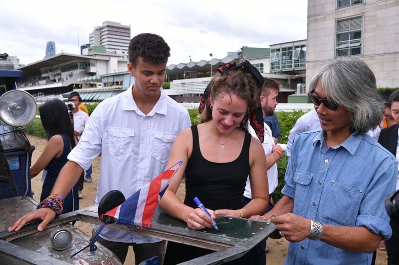 Nathan George, left. Therese-Marie Becker signs an autograph on a Land Rover top drawer for a Thai Land Rover enthusiast.