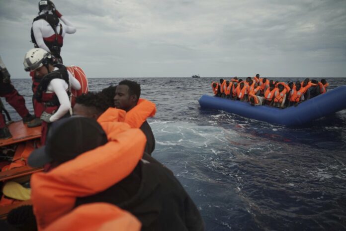 Migrants on a blue rubber boat wait to be rescued some 14 nautical miles from the coast of Libya in Mediterranean Sea, Sunday, Sept. 8, 2019. (AP Photo/Renata Brito)