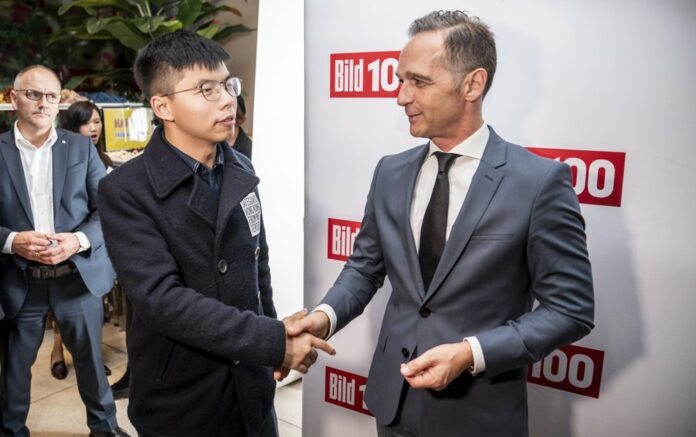 In this Sept. 9, 2019, file photo, German Foreign Minister Heiko Maas, right, and Hong Kong activist Joshua Wong, left, shake hands during a reception of a German newspaper in Berlin, Germany. (Michael Kappeler/dpa via AP, File)