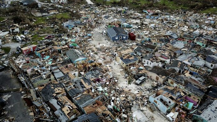 People walk through a neighborhood destroyed by Hurricane Dorian at Marsh Harbour in Great Abaco Island, Bahamas on Thursday, Sept. 5, 2019. Photo: Al Diaz / Miami Herald via AP