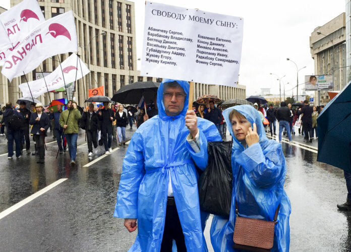 In this photo taken on Aug. 10, 2019, Vyacheslav Abanichev and Alisa Abanicheva, parents of Sergei Abanichev charged with rioting connected to an opposition rally, hold a poster saying 
