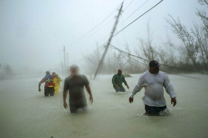Volunteers walk under the wind and rain from Hurricane Dorian through a flooded road as they work to rescue families near the Causarina bridge in Freeport, Grand Bahama, Bahamas, Tuesday, Sept. 3, 2019. The storm’s punishing winds and muddy brown floodwaters devastated thousands of homes, crippled hospitals and trapped people in attics. Photo: Ramon Espinosa / AP